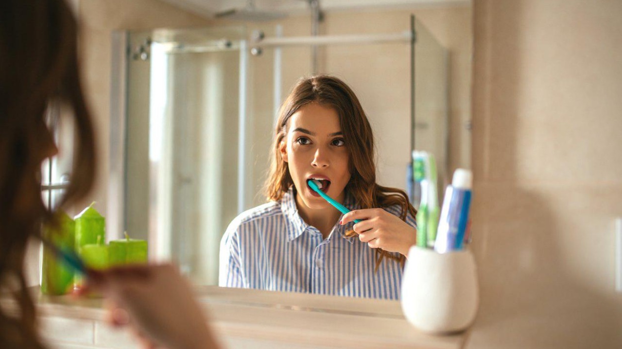 Человек чистит зубы утром в ванной комнате - иллюстрация к статье о том, когда лучше чистить зубы до завтрака или после