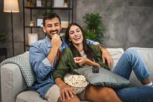 Пара сидит на диване в гостиной — иллюстрация к психологическому тесту о позах партнёров и отношениях