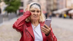 Человек пытается разобраться со смартфоном и испытывает трудности с современными технологиями