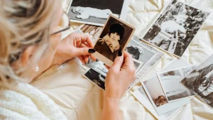 Зрелый человек рассматривает старые фотографии, размышляя о жизненных этапах и изменениях