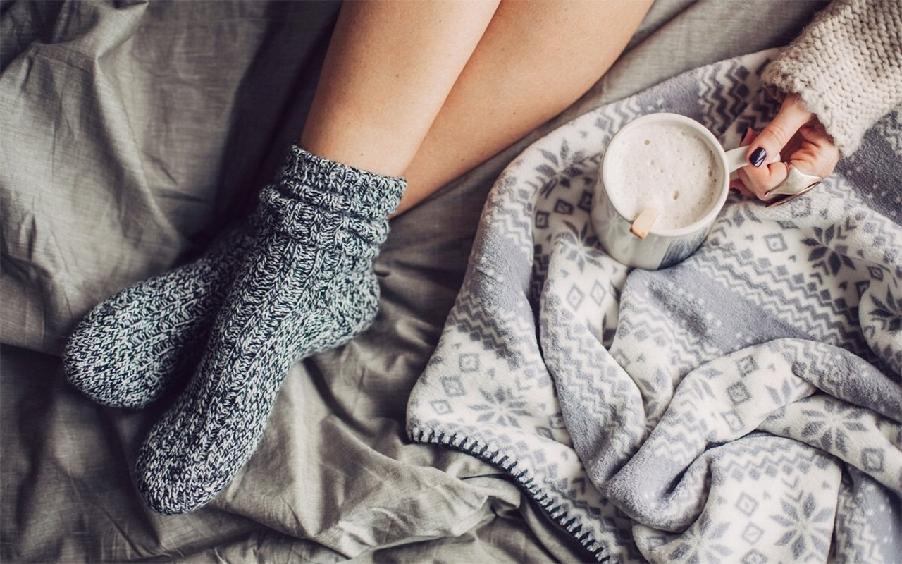 Человек спит в кровати в тёплых носках — символ уюта, комфорта и заботы о себе