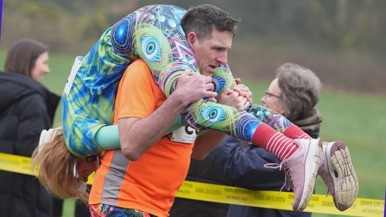 Участник необычного соревнования в Англии несёт партнёршу на спине во время забега по переноске жён.