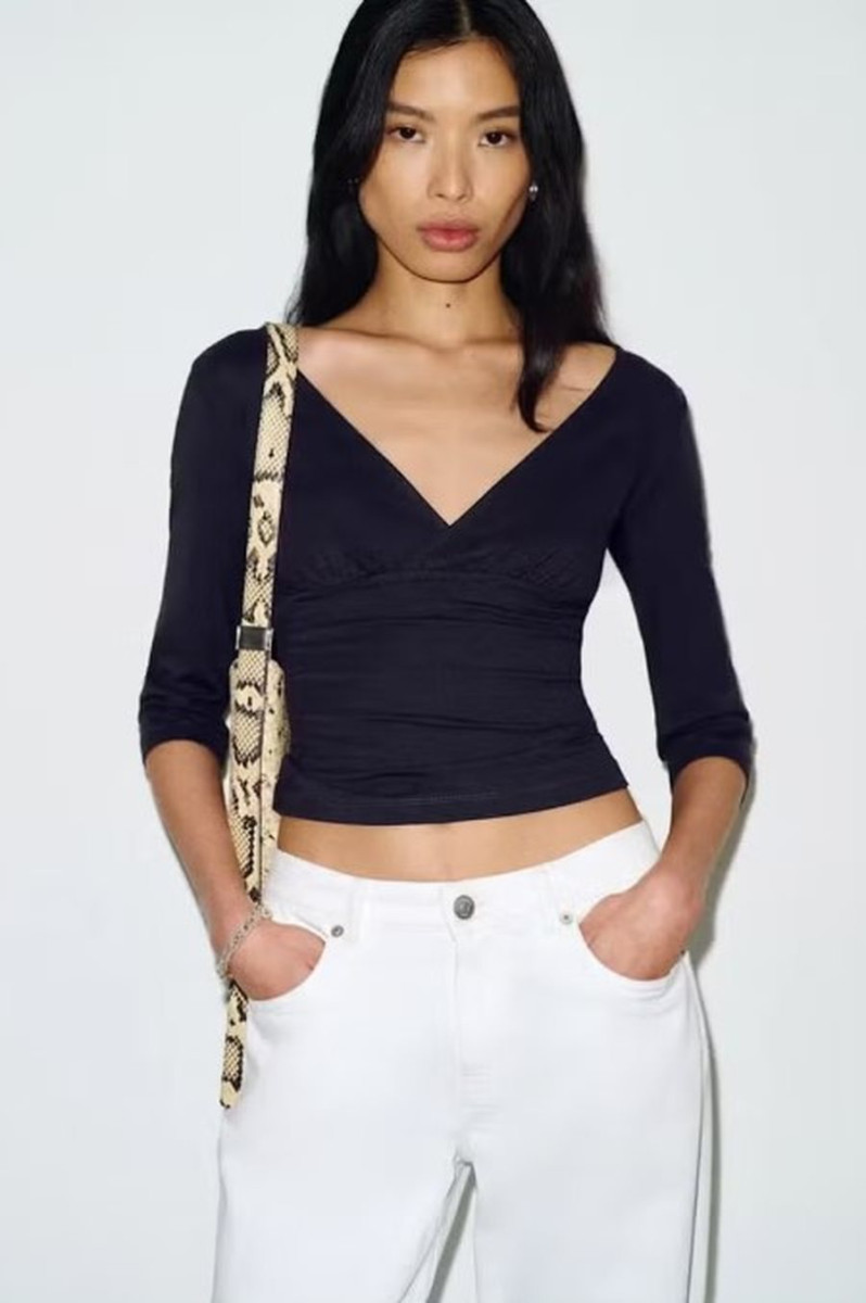 Женщина в минималистичном образе в блузе с рукавом три четверти, весенний стиль в духе 90-х с элегантным силуэтом