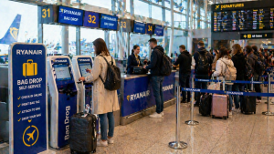 Пассажиры в аэропорту у стойки регистрации багажа и киосков самообслуживания перед вылетом самолёта