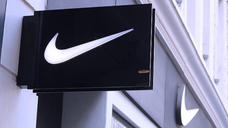 Логотип Nike на фоне магазина компании и заголовков о судебных исках против бренда в США.